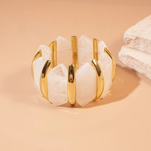 Détail du bracelet en acrylique marbré avec segments dorés sur support en pierre