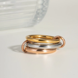 Close-up of interlocking polished gold, silver, and rose gold stainless steel ring bands