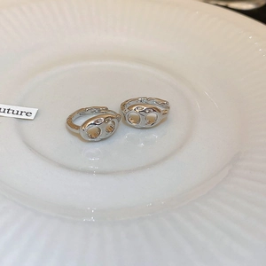 Macro view of silver geometric pig nose earrings on a textured ceramic display tray