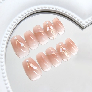 Faux ongles œil de chat rose avec perles blanches et lignes dorées sur plateau