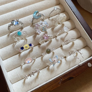 Detailed close-up of various silver rings with pearls and gemstones in a jewelry box