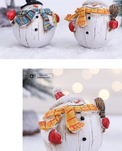 Close-up of resin Christmas snowman ornaments with wood texture and striped scarf details