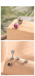 Detail of round zircon screw back cartilage studs in pink, sky blue and navy blue stones