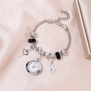 Close-up of silver beaded bracelet watch with heart key charms on pink silk background