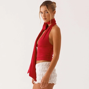Détail du haut dos nu rouge à lanières et du short blanc plissé sur le mannequin