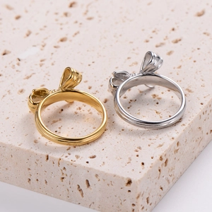 Classic minimalist bow rings in gold and silver finish on a beige textured stone base