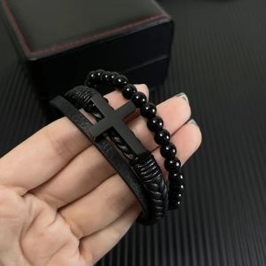 Close-up of black braided leather cross bracelet and bead set in a gift box