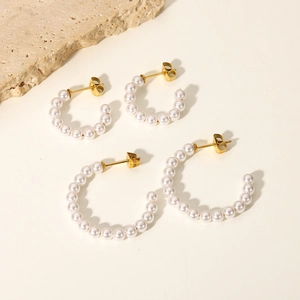 Macro view of C-shaped 18K gold plated stainless steel earrings with tiny white pearls