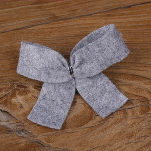 Macro detail of a grey felt Christmas bow with dual layers and metal ring fastener