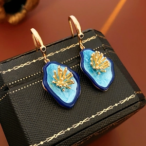 Macro shot of vintage gold earrings with irregular blue enamel flowers on retro jewelry box