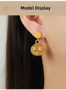 Detail of vintage hollow geometric sphere earrings in gold with zircon inlay on model