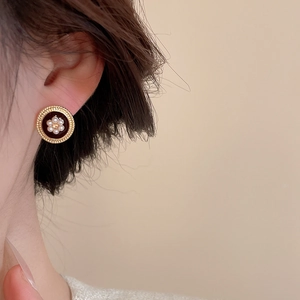 Close-up of vintage round gold earrings with dark brown enamel and pearl flower details