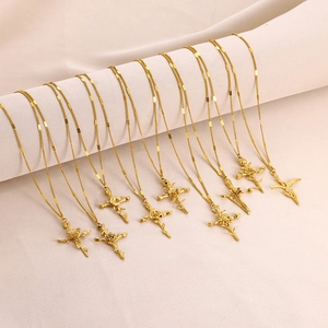 Gold-plated 3D December flower cross necklaces for women displayed on a cream fabric roll