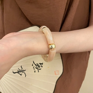 Detail of bamboo-shaped resin bead bracelet with marble texture and gold metal accents