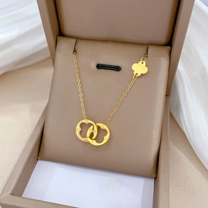 Detail of gold titanium steel necklace with double interlocking rings and clover charm