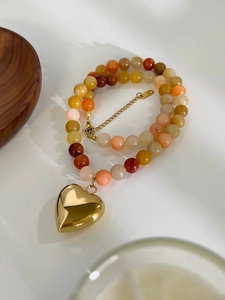 Detail of colorful beaded necklace with golden heart pendant and adjustable metal chain