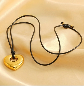 Detailed macro view of the polished golden hollow heart pendant on a black cord