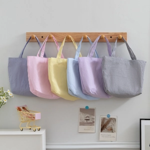 Set of six striped canvas tote bags in pastel colors hanging on wooden hooks