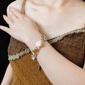 Vue détaillée d'un bracelet en coquillages irréguliers blanc et marron au poignet