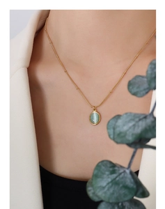 Close-up of a 18k gold plated titanium necklace with green cat-eye opal pendant on neck