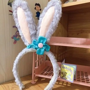 Détail d'un bandeau oreilles de lapin en peluche violet clair avec fleur de satin bleu