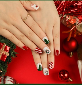 Close-up of Christmas press-on nails with festive reindeer and holiday tree patterns