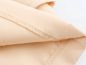 Detailed close-up of neat stitching and textured beige fabric on the asymmetric skort