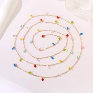 Detail of golden chain necklace with colorful translucent teardrop charms in a spiral layout