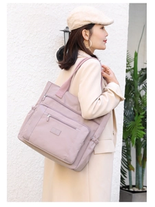 Gros plan d'un grand sac bandoulière lilas avec plusieurs poches zippées sur un modèle