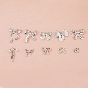 Détail de dix pendentifs nœuds en acier inoxydable argenté de différentes tailles