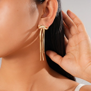 Macro shot of 18K gold plated bow earrings with dangling tassels and sparkling zircons