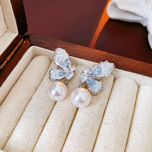 Detail of silver butterfly earrings with zircons and teardrop pearls in a jewelry box