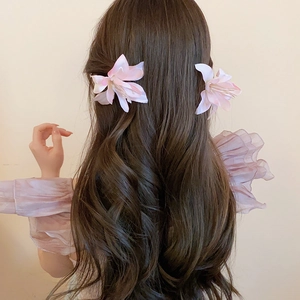 Close-up of pink fabric hibiscus hair clips with delicate silk petals on long wavy hair