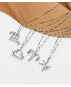 Close-up of four silver zodiac necklaces with micro-pave crystals on display
