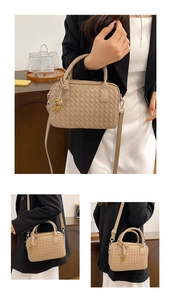 Detail view of woven leather texture and golden hardware on the beige Boston handbag