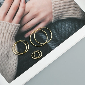 Detailed view of three sizes of minimalist polished gold S925 silver hoop earrings