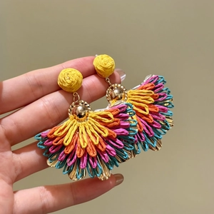 Detailed macro shot of multi-colored raffia fan earrings with gold-tone accents.