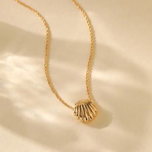 Close-up of gold 18K plated shell pendant necklace with zircon and textured details