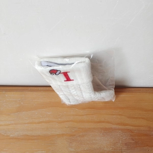 Detail of white knitted Christmas stocking with red embroidered letter I and Santa hat