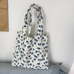 Detailed view of canvas tote bag with vintage blue berry patterns on creamy white fabric