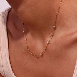 Elegant gold titanium necklace with sparkling floral and circular zircon pendants on a model