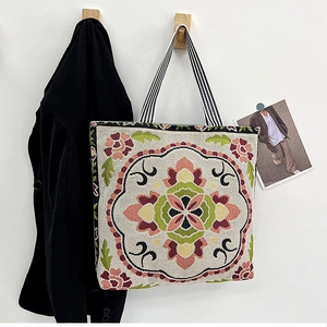 Detail of vintage floral embroidery on canvas tote bag with striped shoulder strap