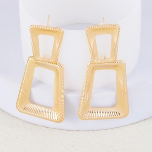 Detailed macro view of large golden geometric earrings with radial textures on white stand