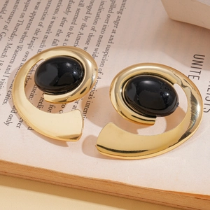 Detailed close-up of retro spiral gold earrings with oval black stones on book pages