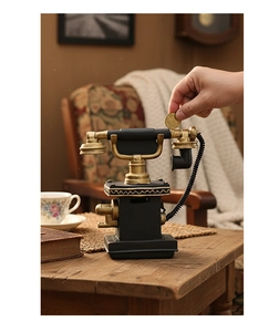 Detalle de hucha con forma de teléfono vintage en acabado negro y toques dorados