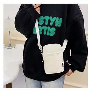Detailed view of a white canvas crossbody bag with adjustable strap and sport tag detail