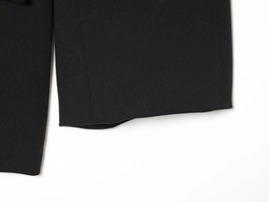 Detail shot of black blazer hem showing twill fabric texture and stitched bottom edge