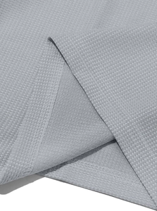 Detailed macro view of light gray waffle weave fabric texture on men's long sleeve henley shirt