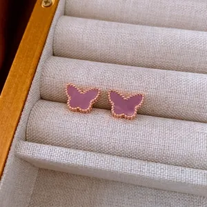 Rose gold butterfly stud earrings with pink inlay and beaded edges on a jewelry box