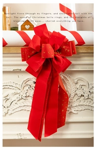Detail of red velvet Christmas bow with gold foil star patterns on white fireplace